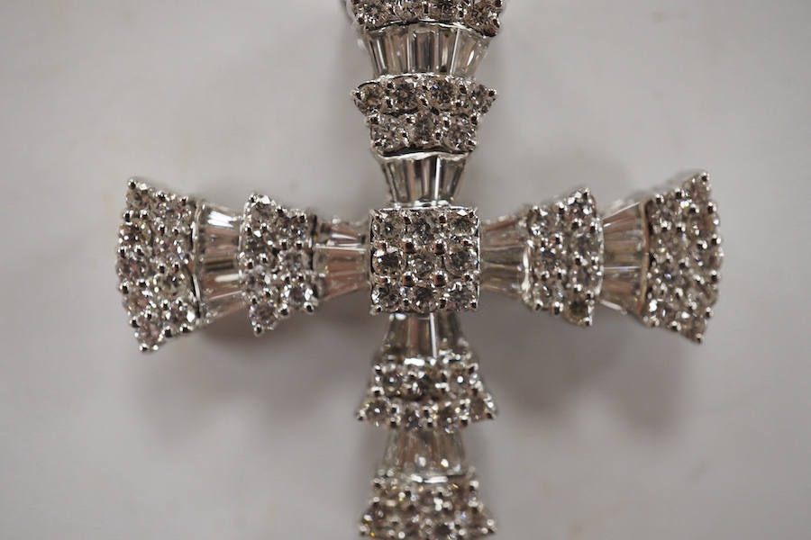 A modern 750 white metal, round and tapered baguette cut diamond cluster set cross pendant, 42mm, gross weight 7.2 grams. Condition - fair to good